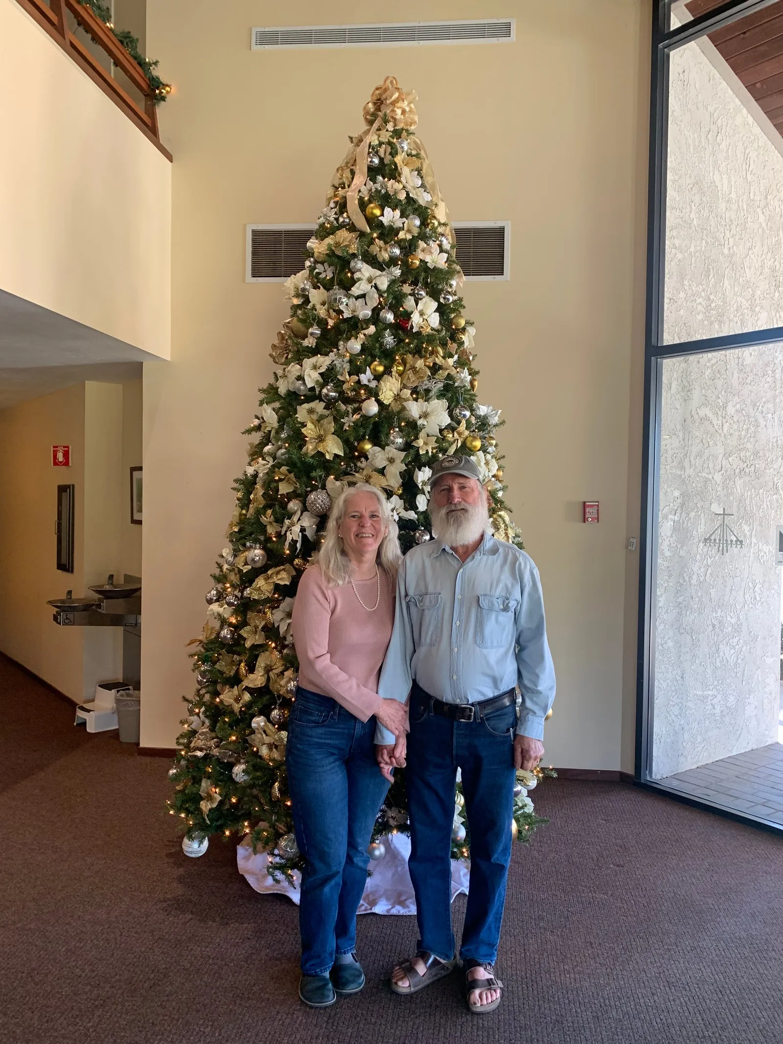 My parents enjoying the holiday spirit in front of the church Christmas tree